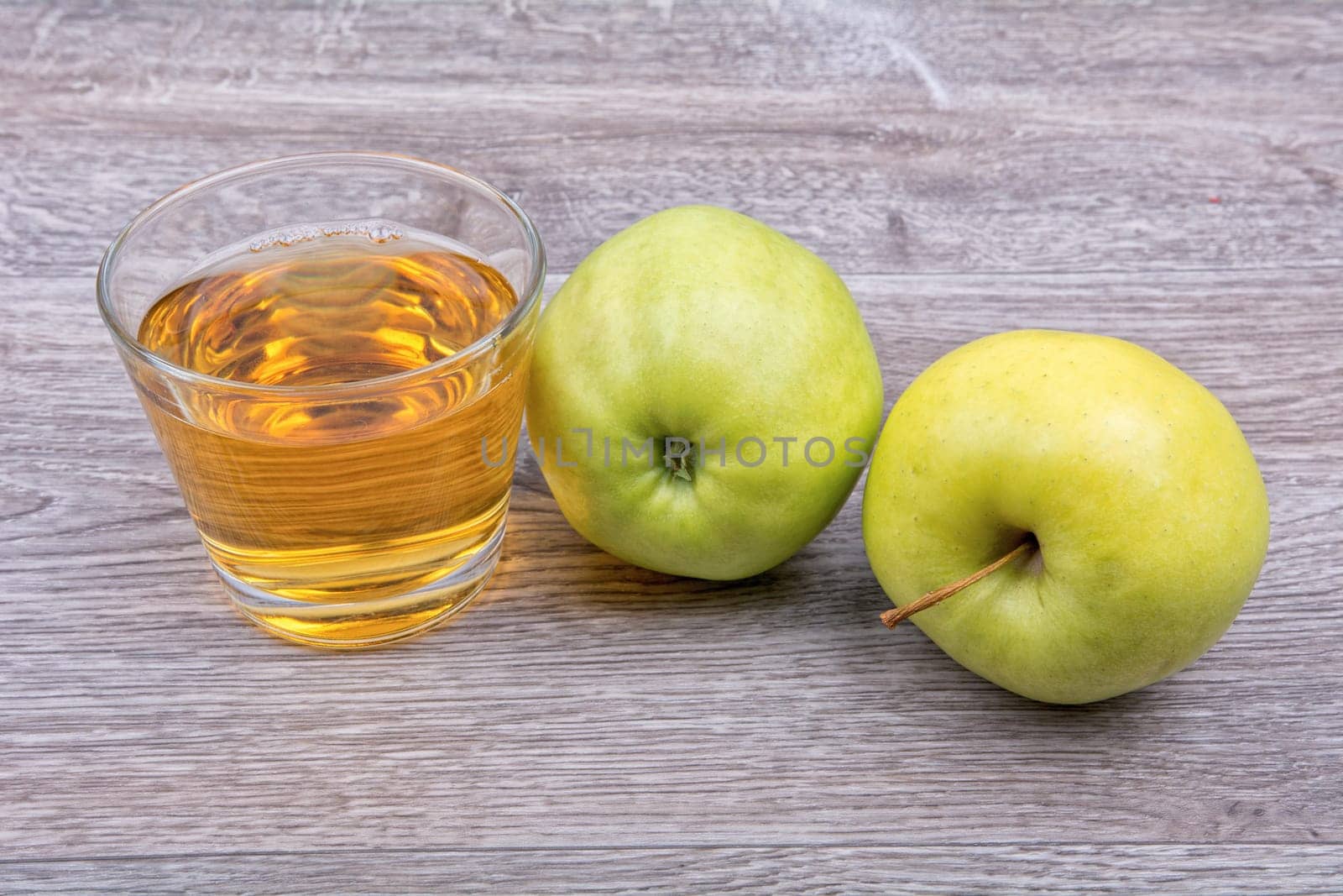 Green apples and juice on a wooden background