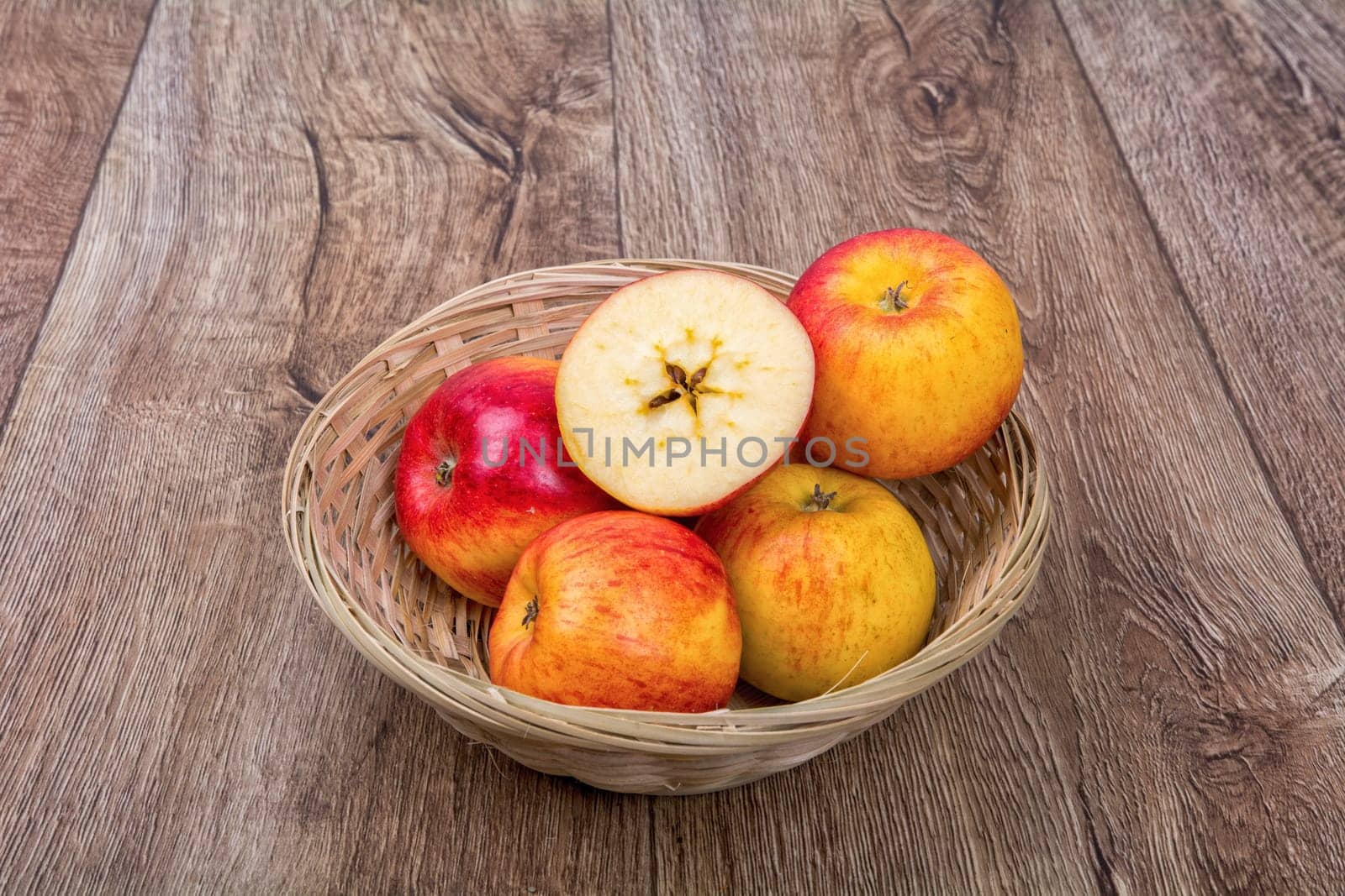 Apples in a knitted bowl on a brown wooden background