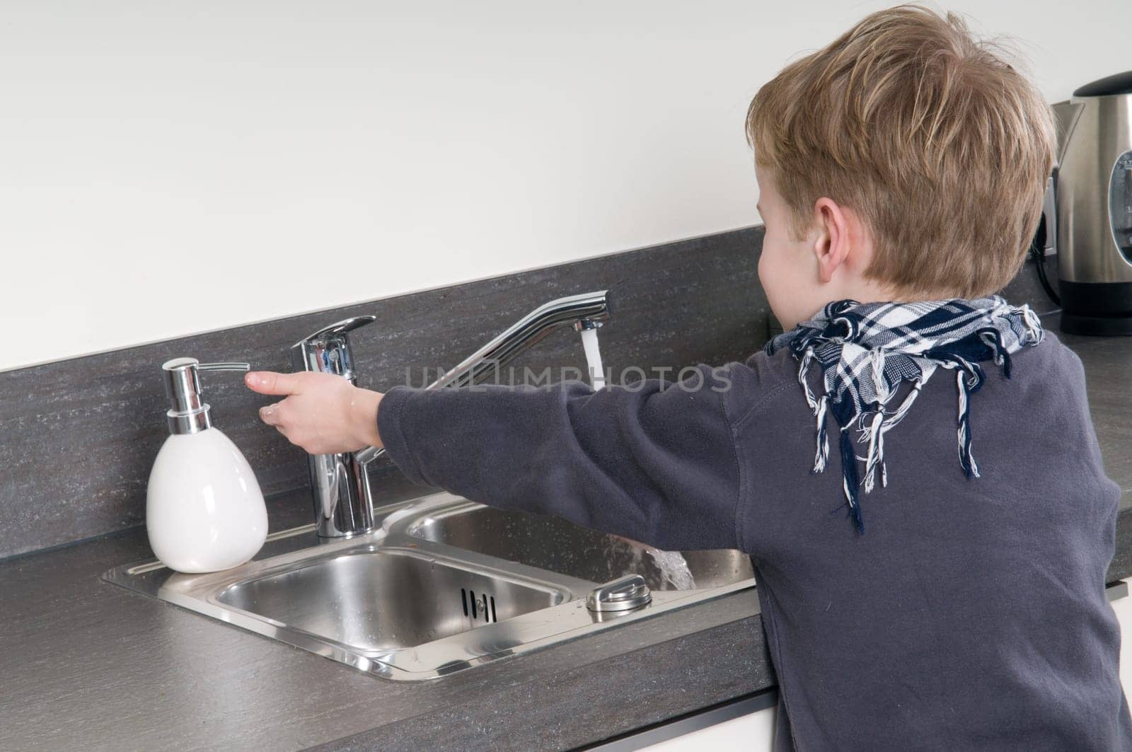 Child washing his hands before he is going cooking.