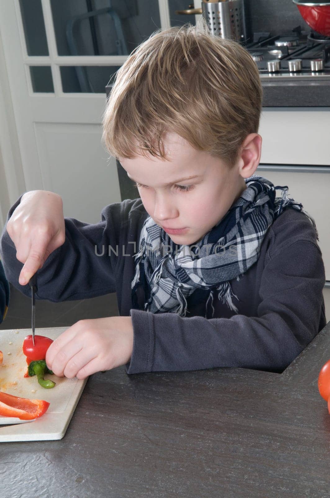 Boy cutting a red pepper, getting ready to cook.