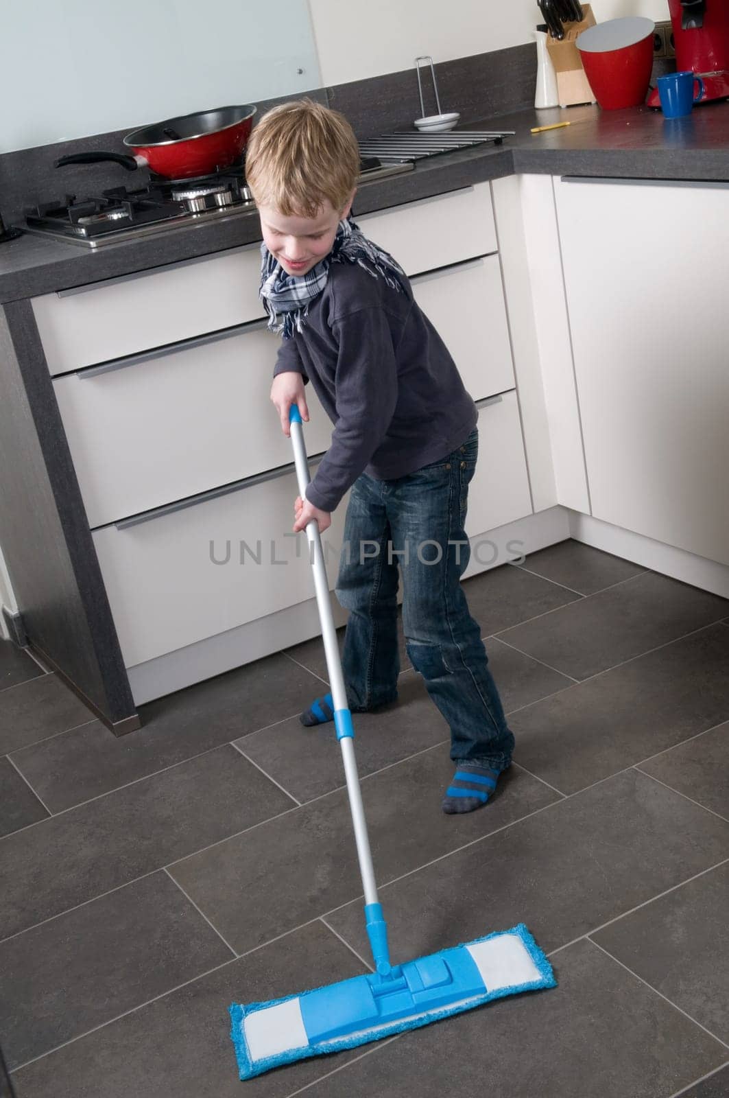 Young boy is learning how to clean a floor