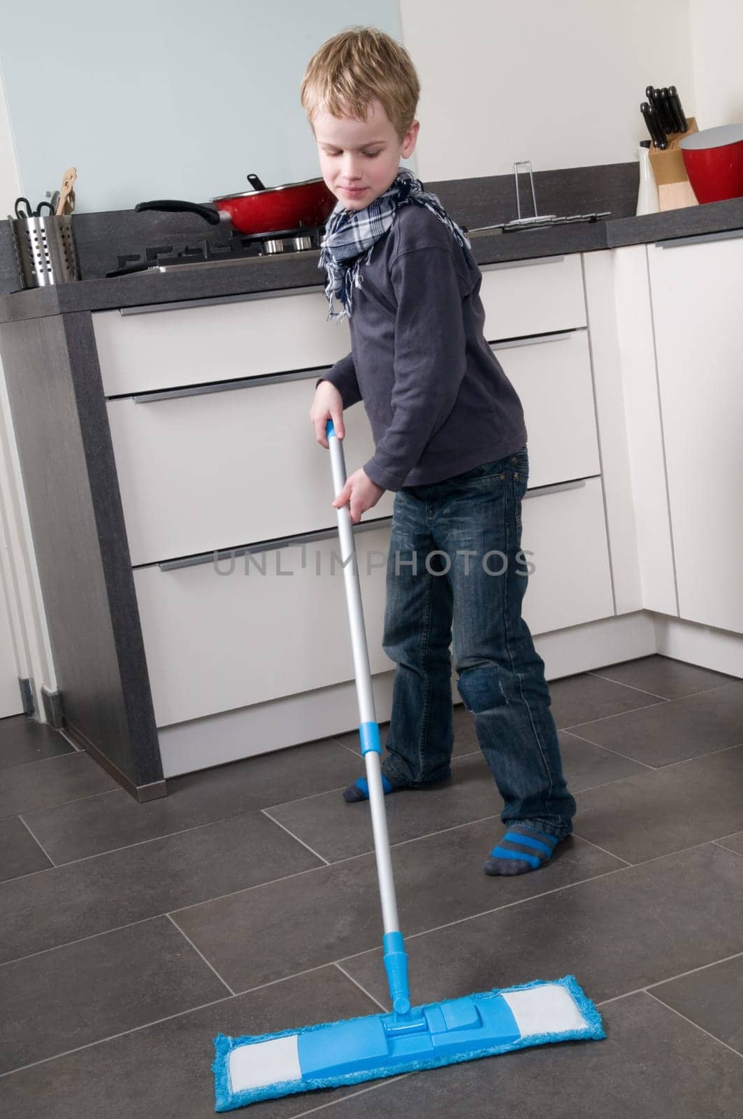 Young boy is learning how to clean a floor