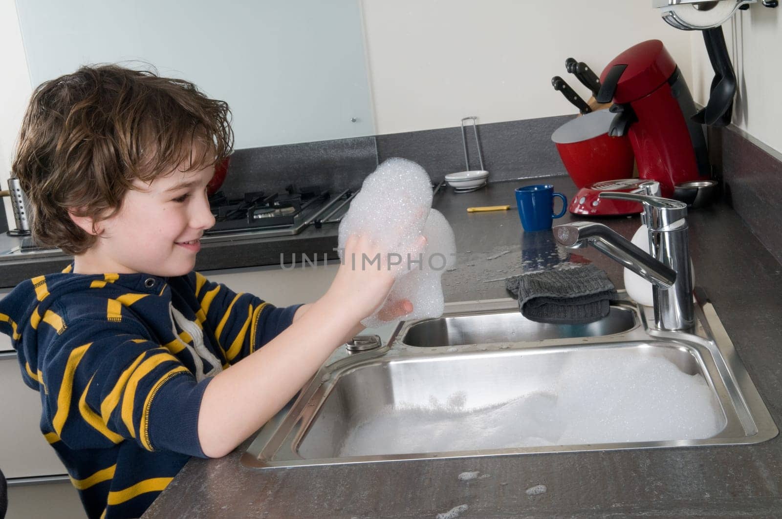Boy having fun with soap while doing the dishes