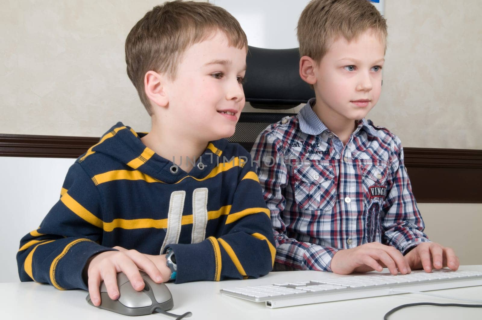 Two friends are having fun while working on a computer.