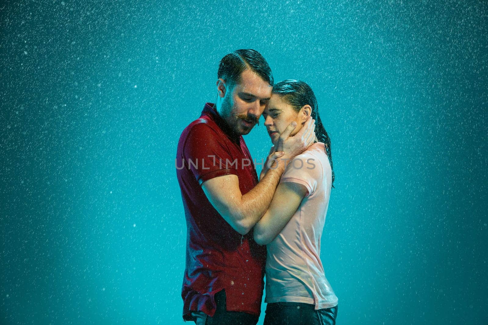 The loving couple kissing in the rain on a turquoise background