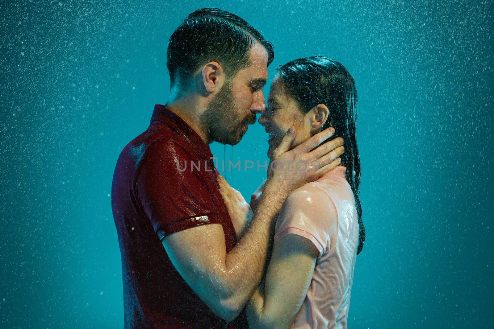 The loving couple kissing in the rain on a turquoise background