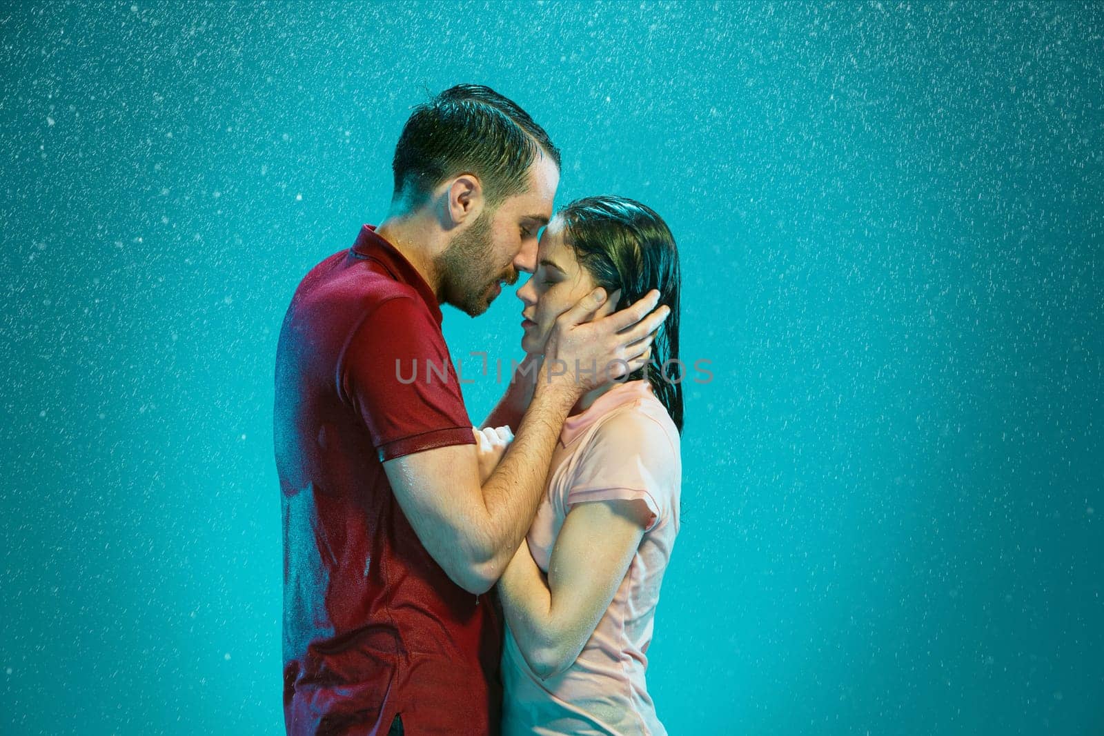 The loving couple kissing in the rain on a turquoise background