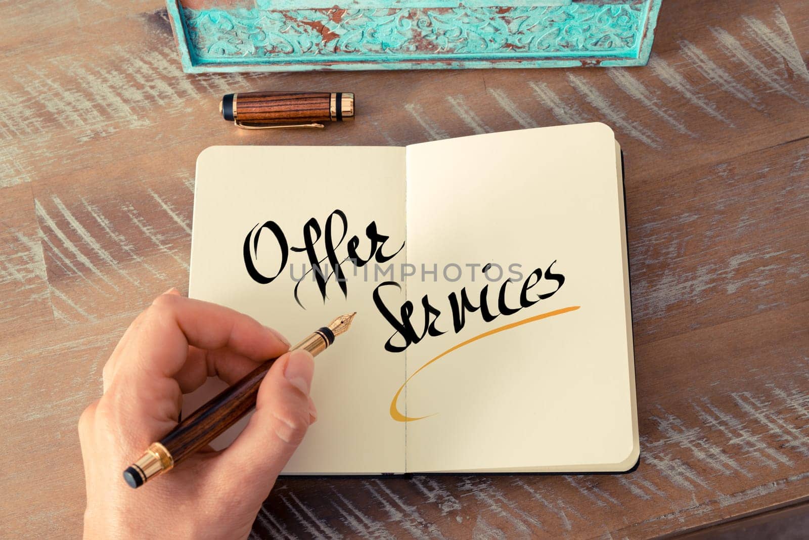 Retro effect and toned image of a woman hand writing a note with a fountain pen on a notebook. Handwritten text Offer Services as business concept image