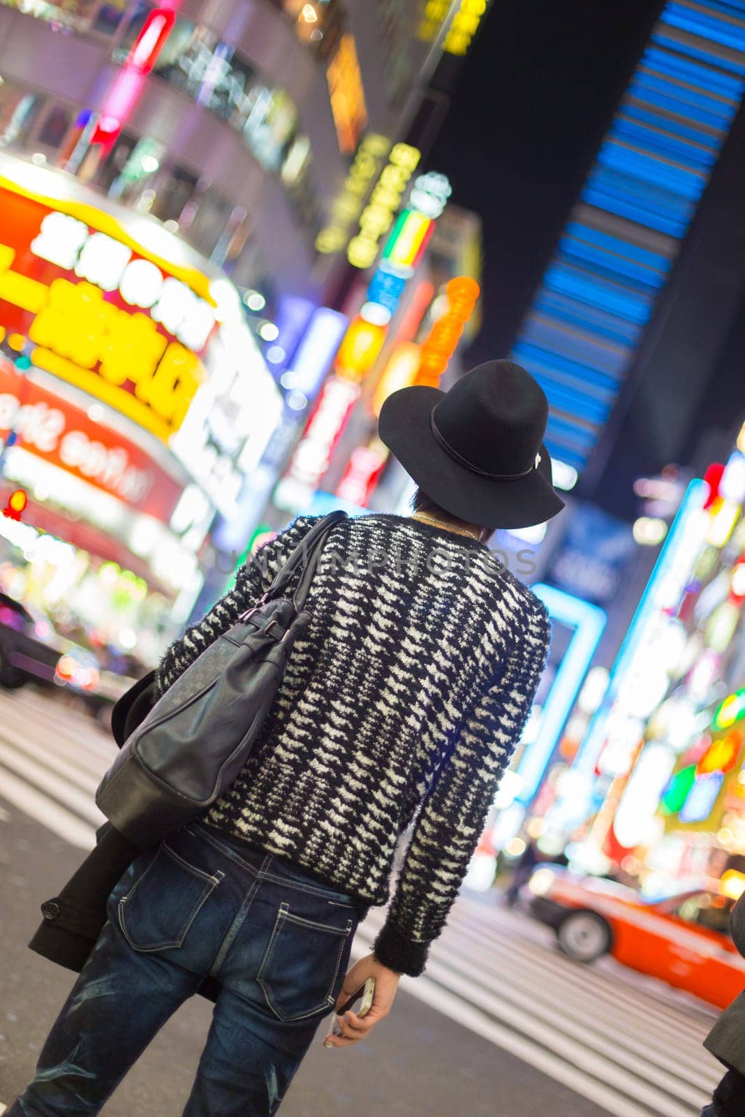 Solitary fashionably dressed young man waiting on crossroad in Kabukicho, entertainment and red-light district in Shinjuku, Tokyo, Japan.