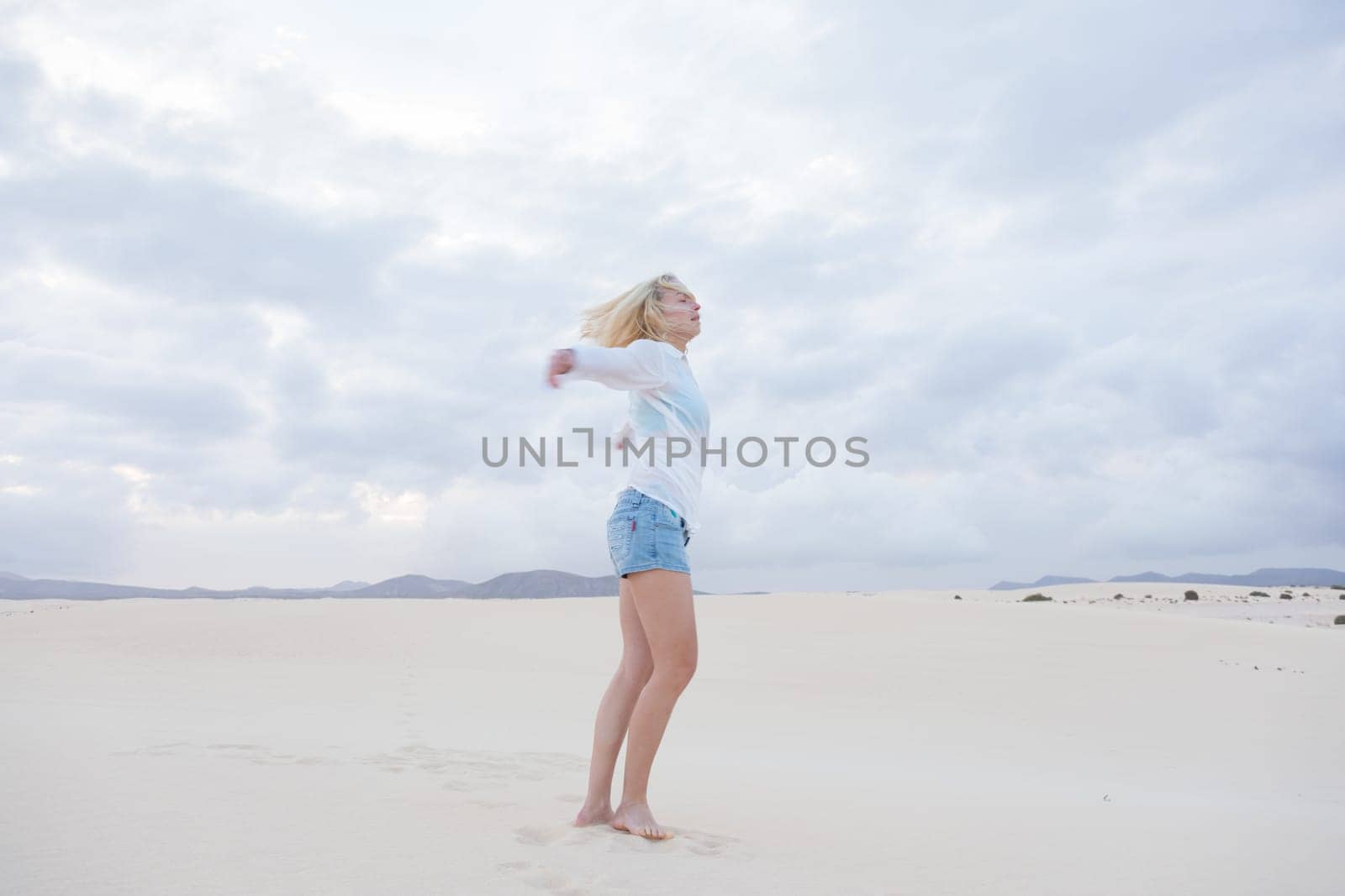 Relaxed woman enjoying freedom feeling happy at beach in the morning. Serene relaxing woman in pure happiness and elated enjoyment with arms outstretched.