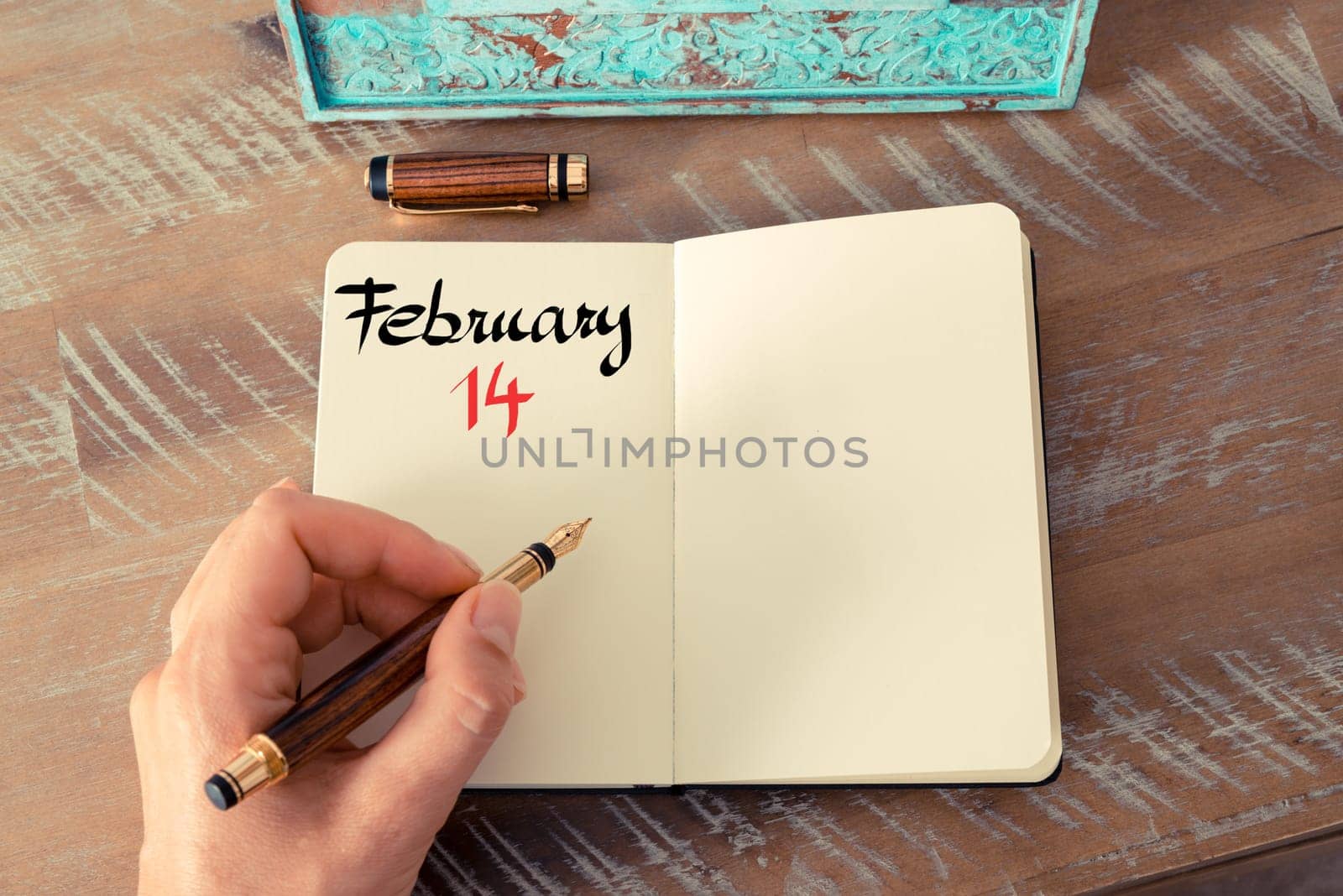 Concept image of February 14 Calendar Day with empty space for text as handwritten note with fountain pen on a notebook