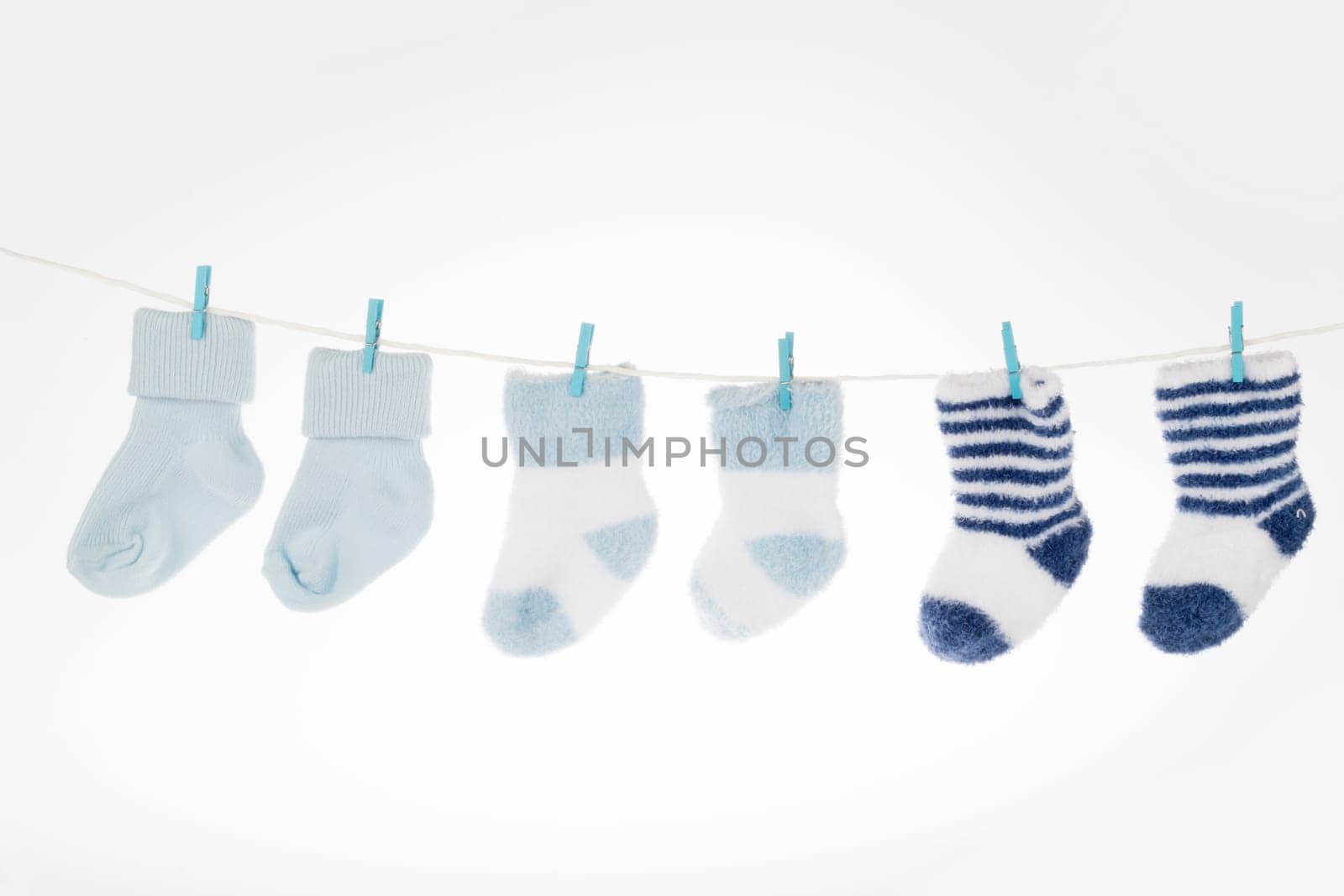 Blue and white baby socks on clothesline, isolated on white background