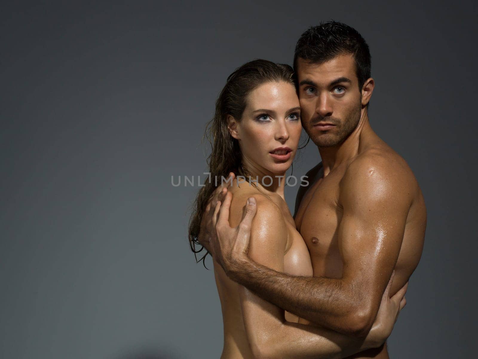 man and woman with nude torso foreplaying in grey background