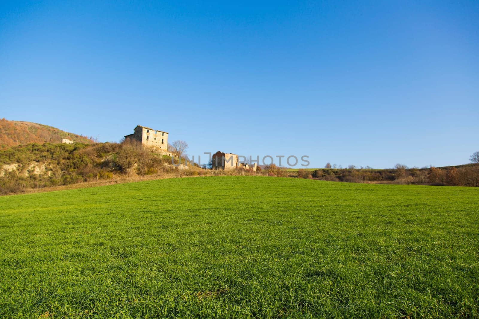 Panoramic view of a field for the agriculture with an old farm in the background
