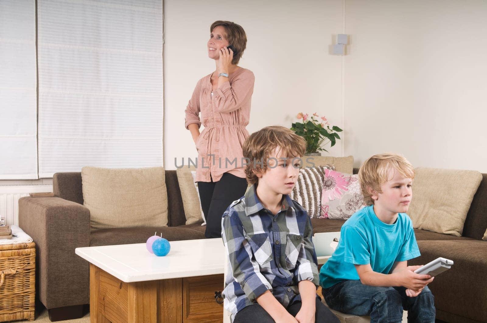 Children are watching tv while mother is calling in the background