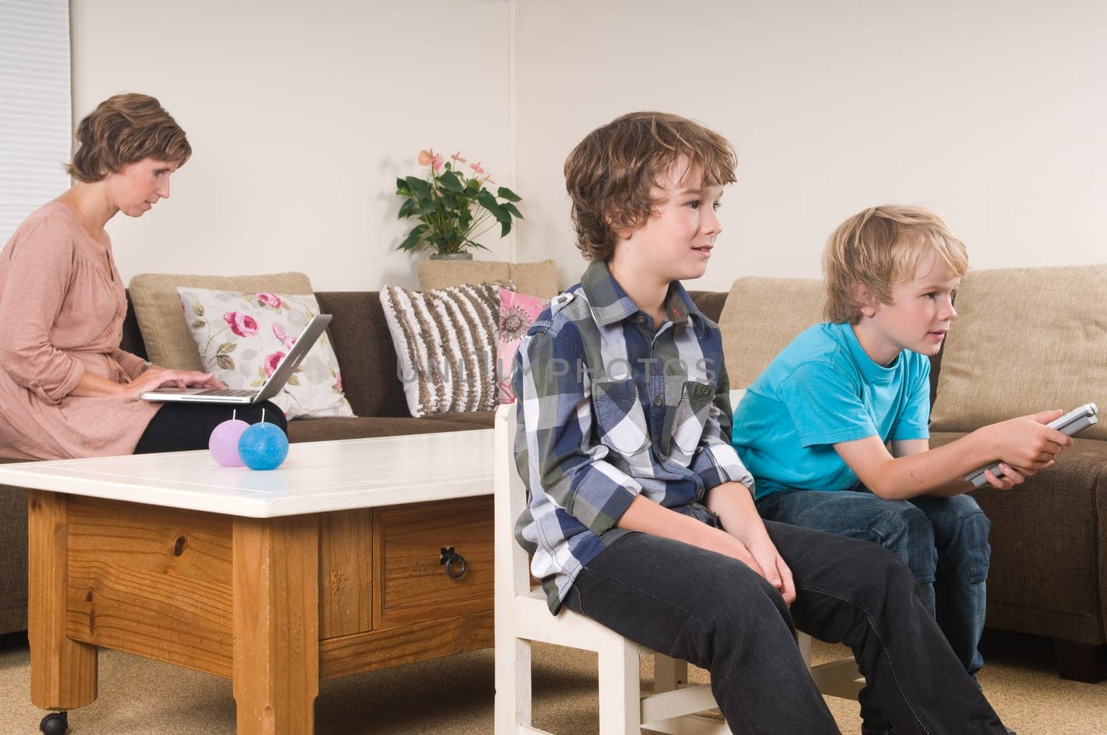 Children are watching tv while mother is working in the background