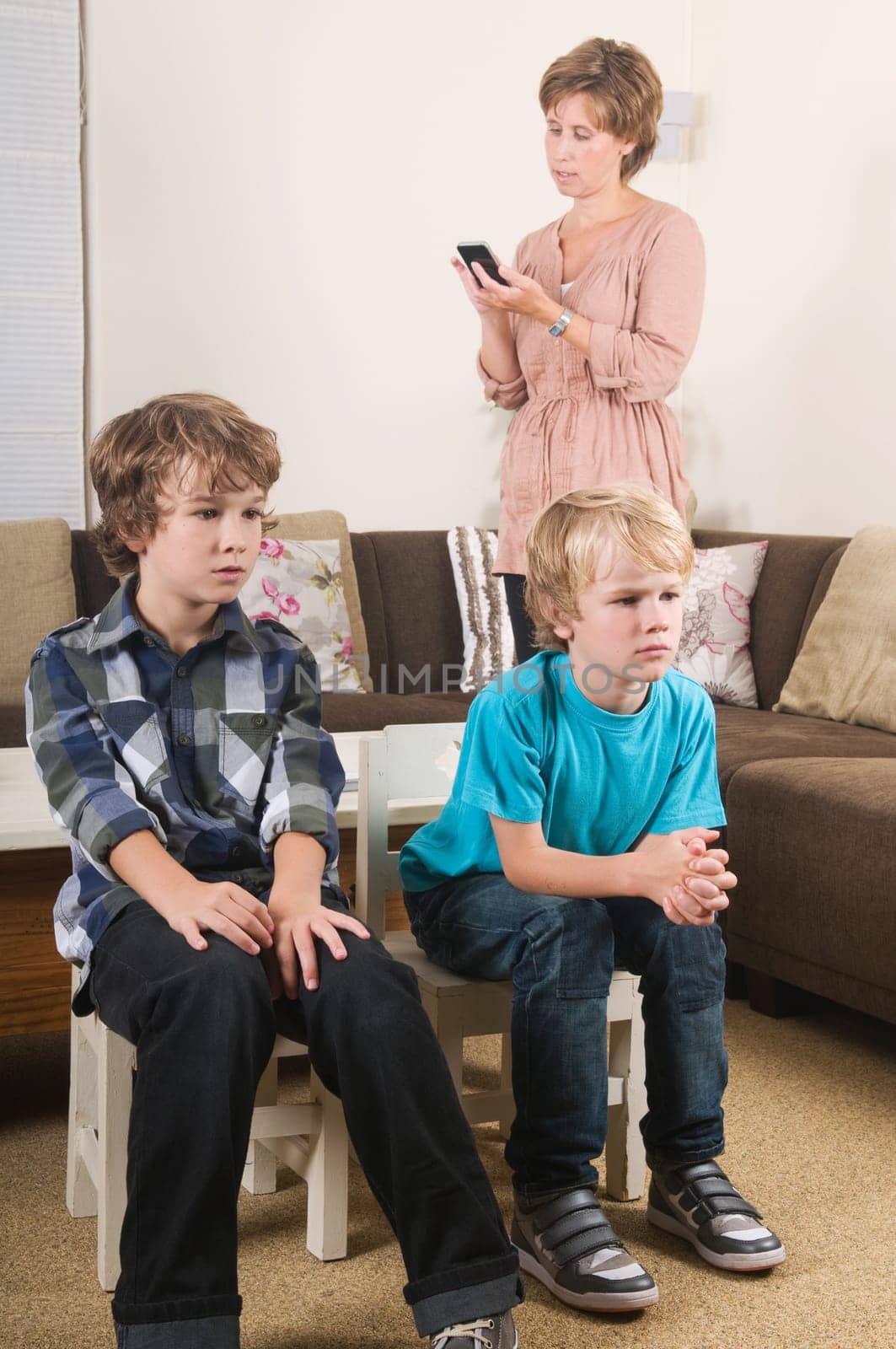 Children are watching tv while mother is calling in the background