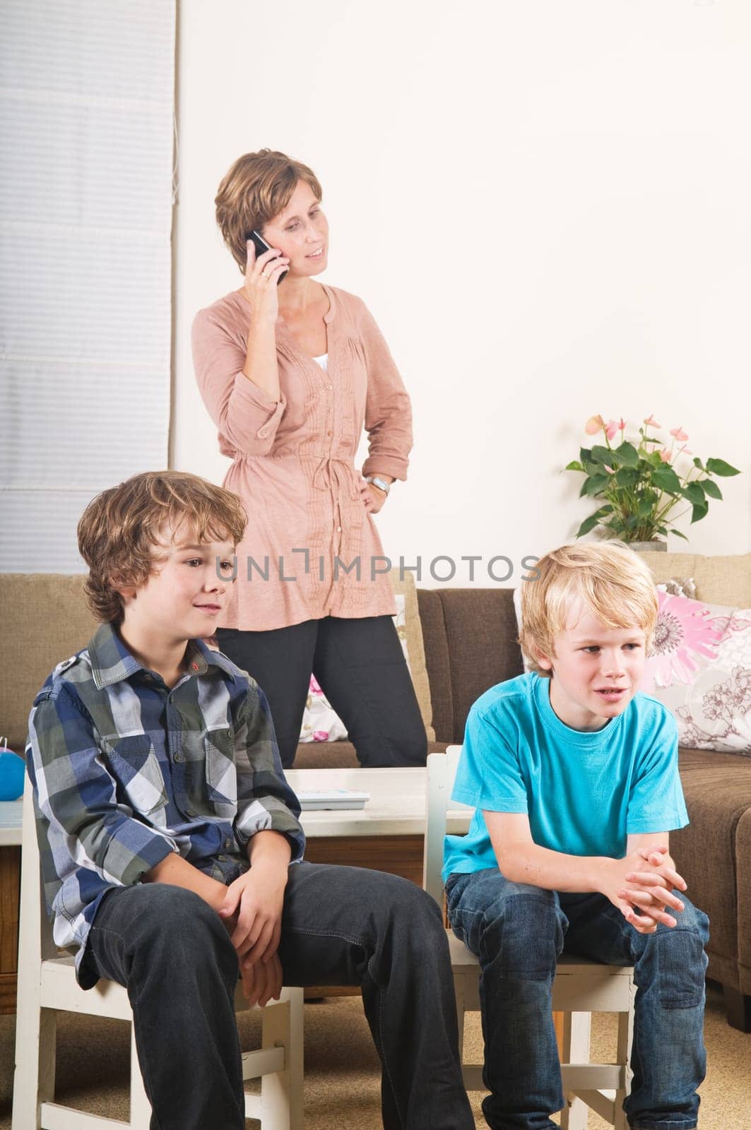 Children are watching tv while mother is calling in the background