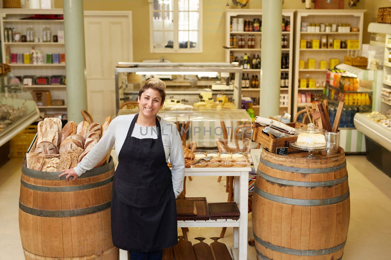 A young deli employee standing in front of the pastry display