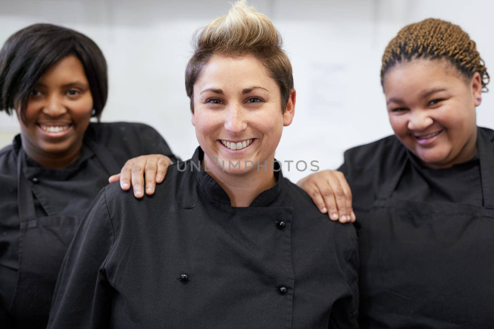 Three chefs standing together inside white kitchen