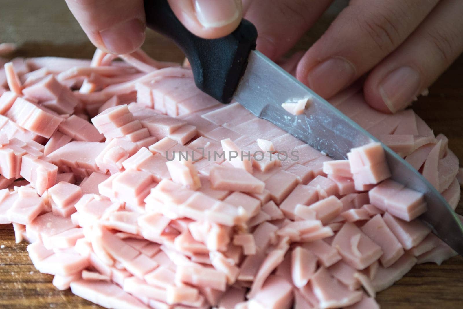 Closeup of salami beeing cutted with knife.