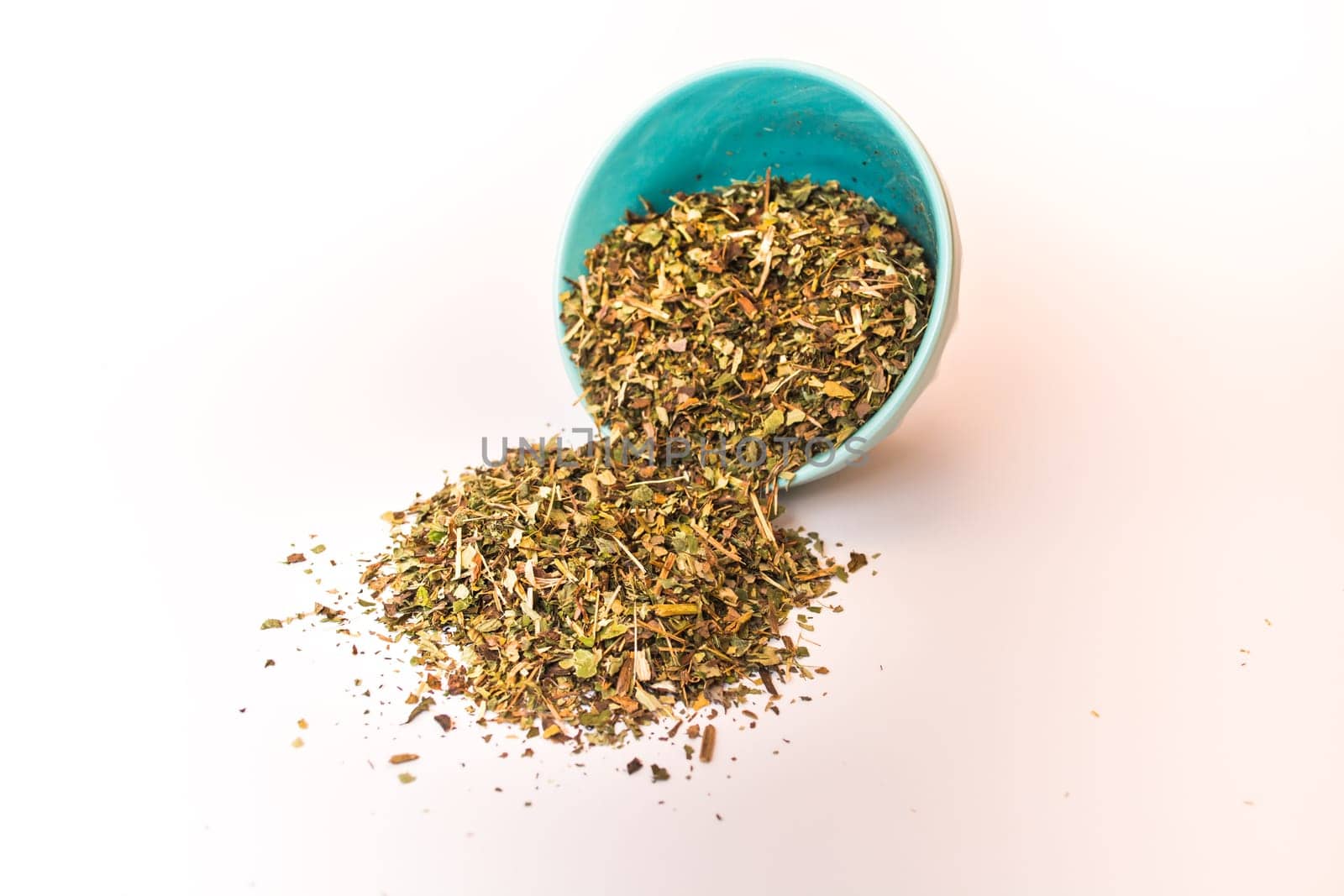 Spilled tea herb in bowl on white background