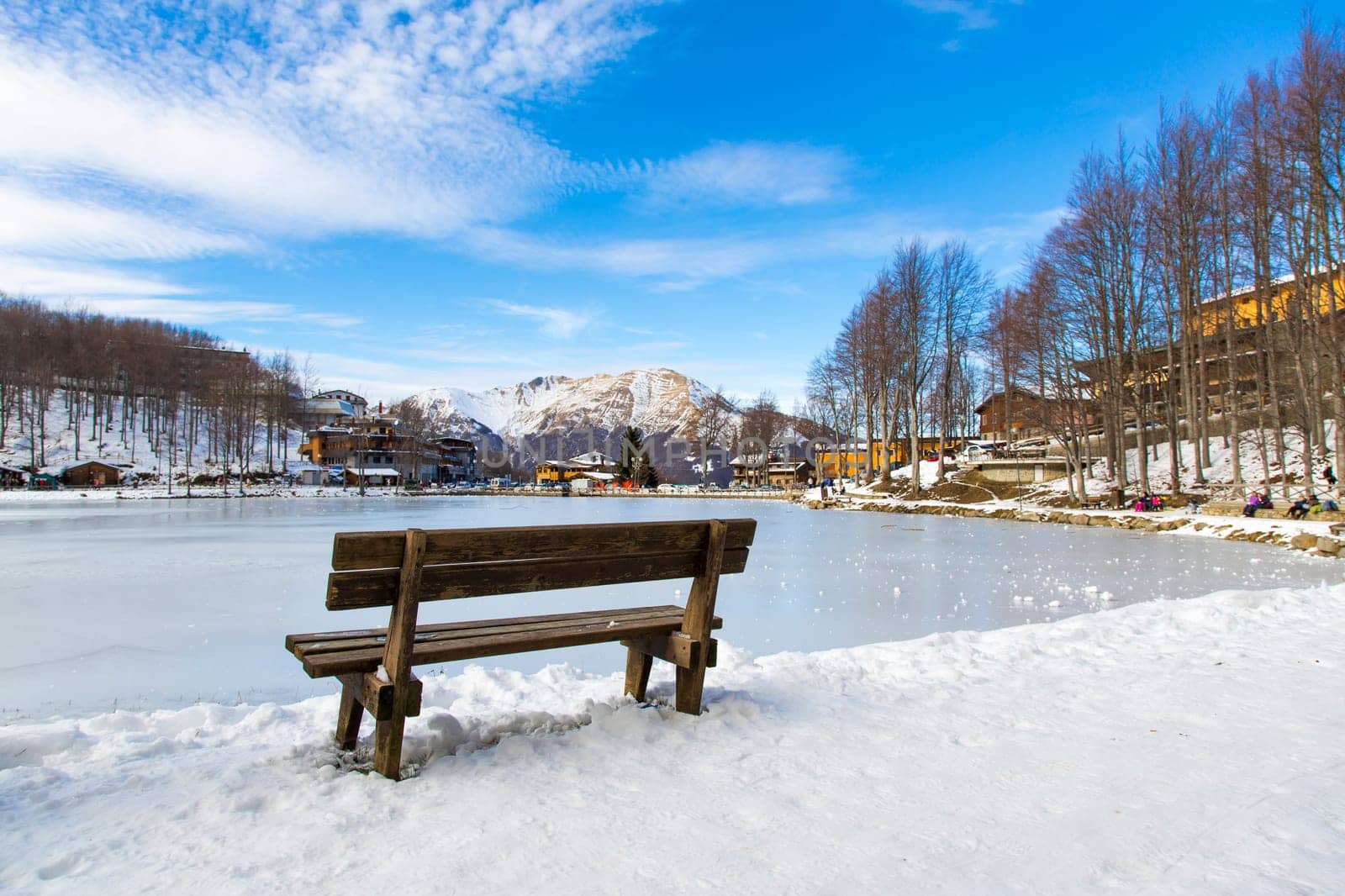 View from the back of a wooden bench in a Tuscan snowy landscape