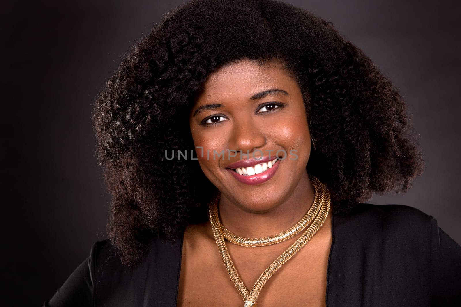 beautiful young black woman is wearing dark dress on grey background