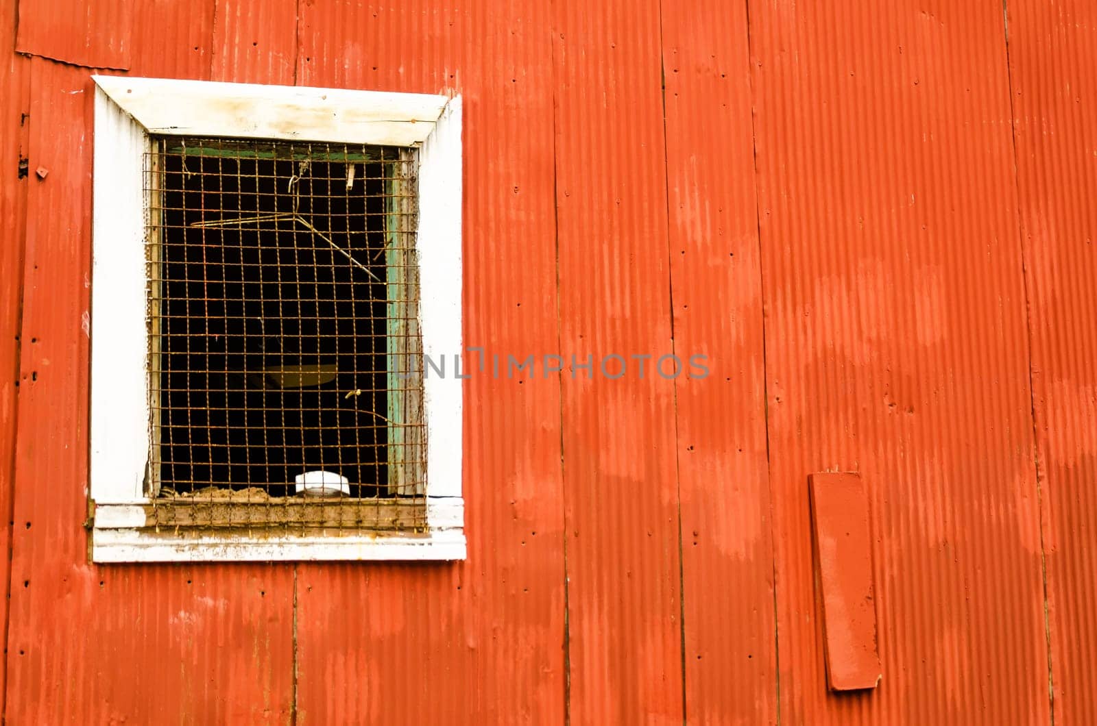 Window on a red corrugated metal wall in Valparaiso, Chile