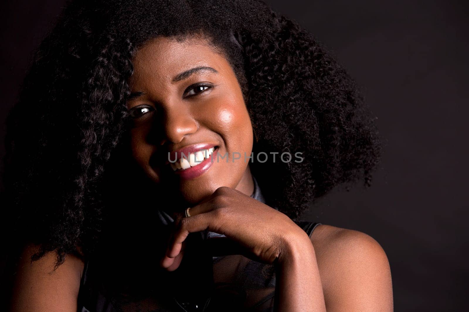 beautiful young black woman is wearing dark dress on grey background