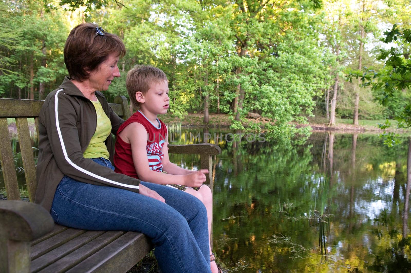 Grandma and her grandson are sitting on a bench.