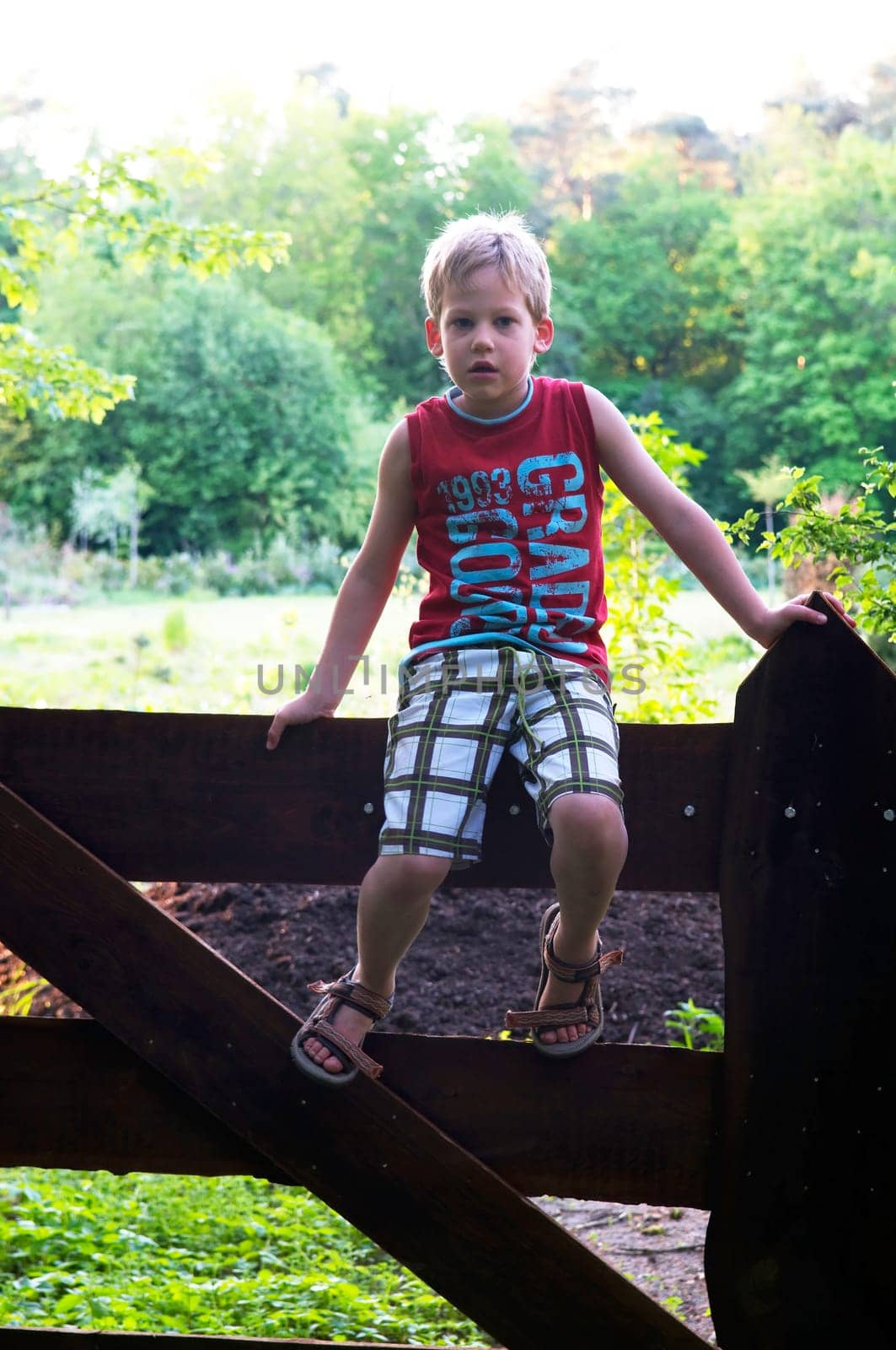 Backlit picture of a boy on a fence.