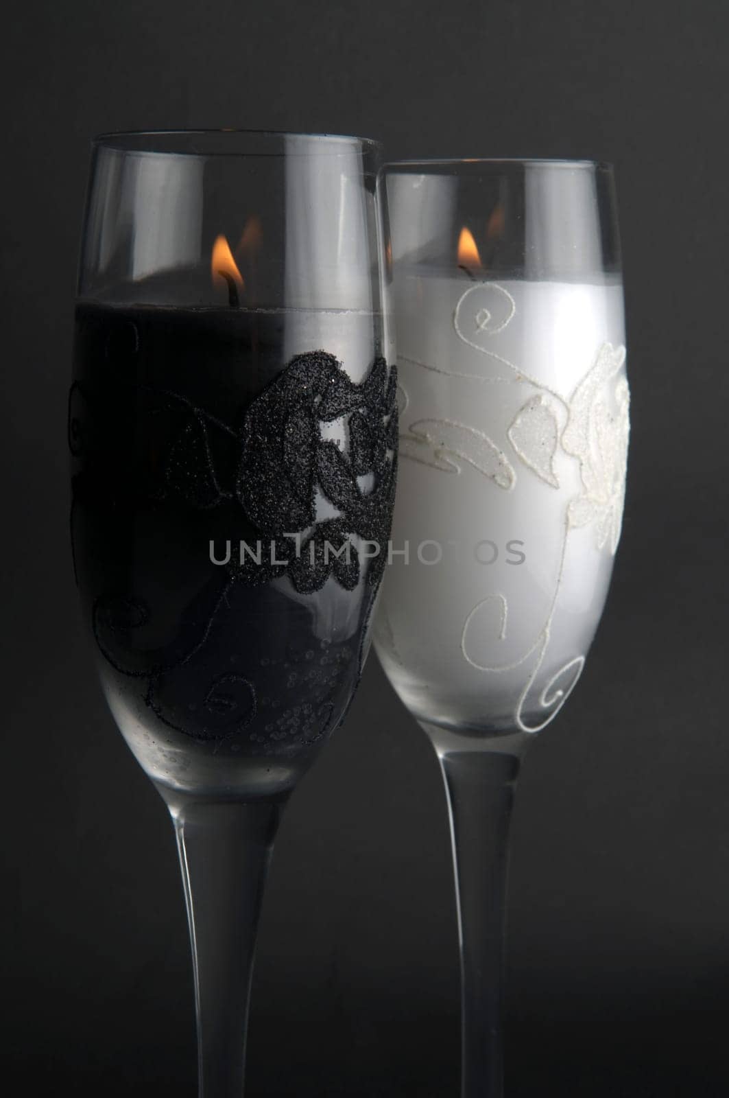 Candles in glasses, against a black background.
