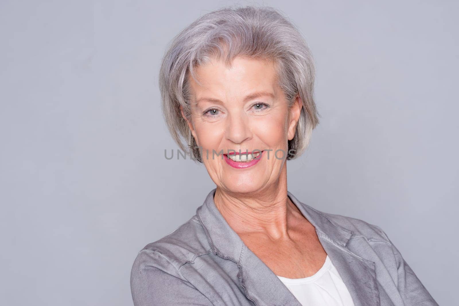 Studio recording of an active senior woman against a grey background