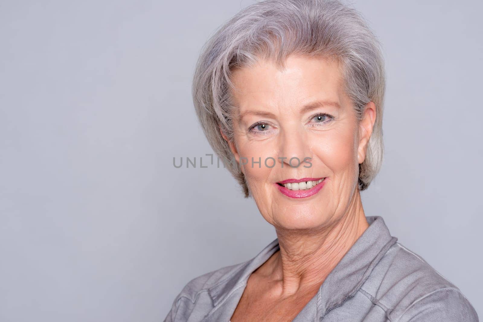 Studio recording of an active senior woman against a grey background