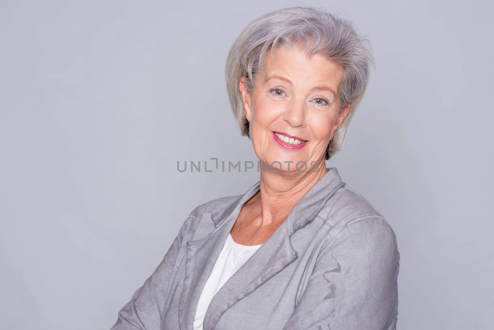 Studio recording of an active senior woman against a grey background