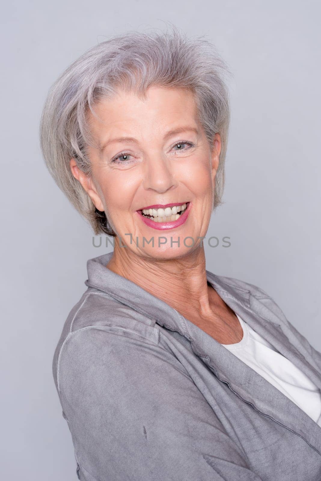 Studio recording of an active senior woman against a grey background