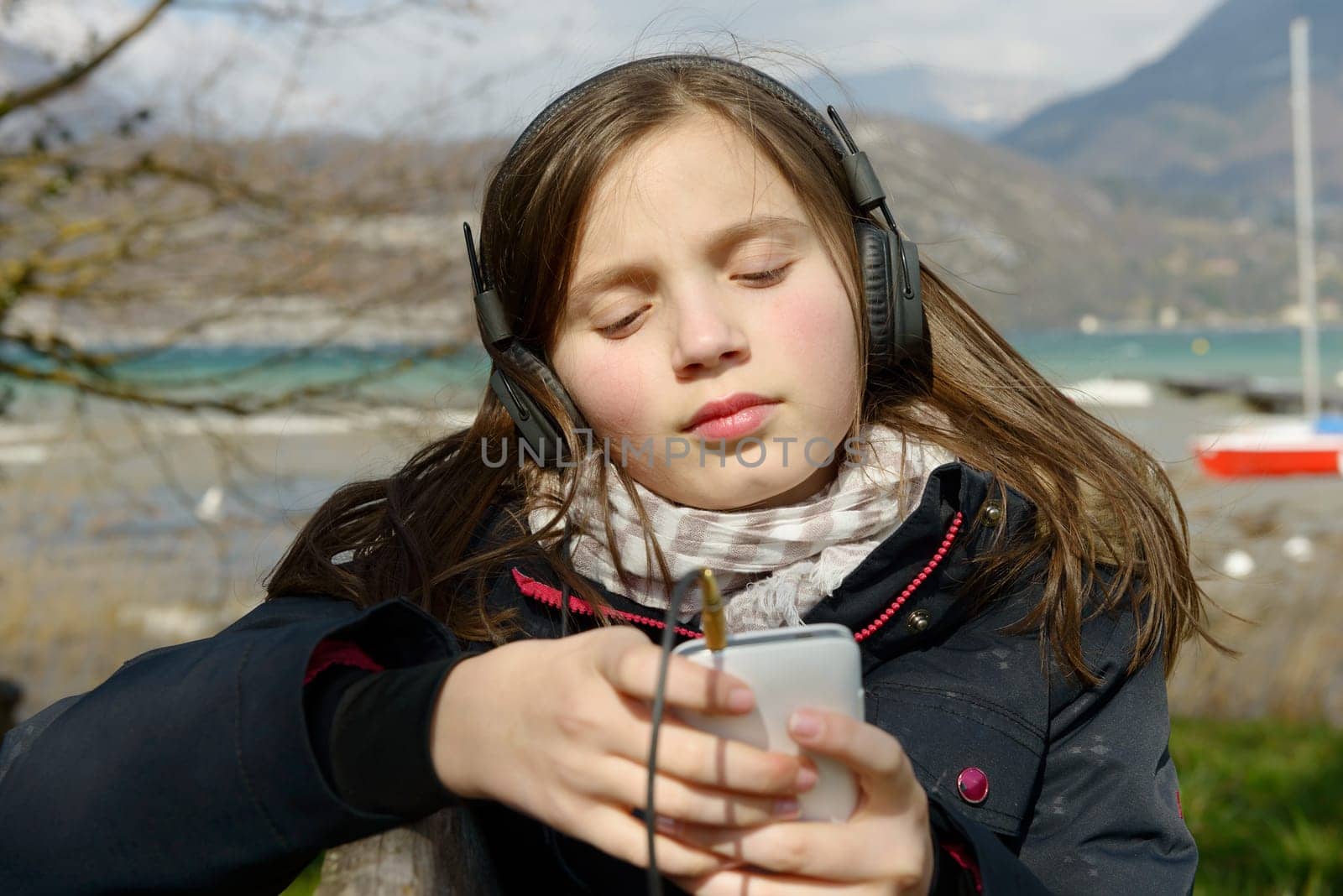 a young teenager listening to music on his phone, outdoor