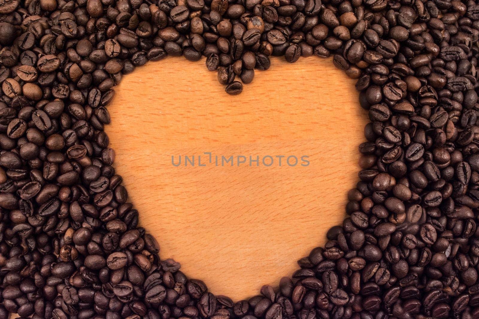 Heart formed with coffee beans on wooden table
