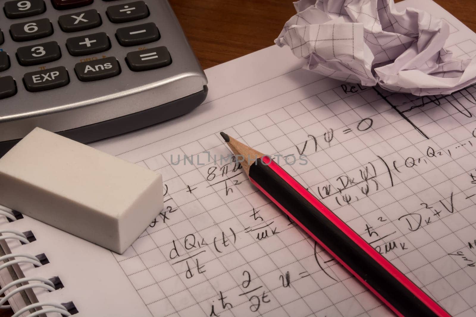 Messy table with notebook, pencils, crumpled papers and calculator
