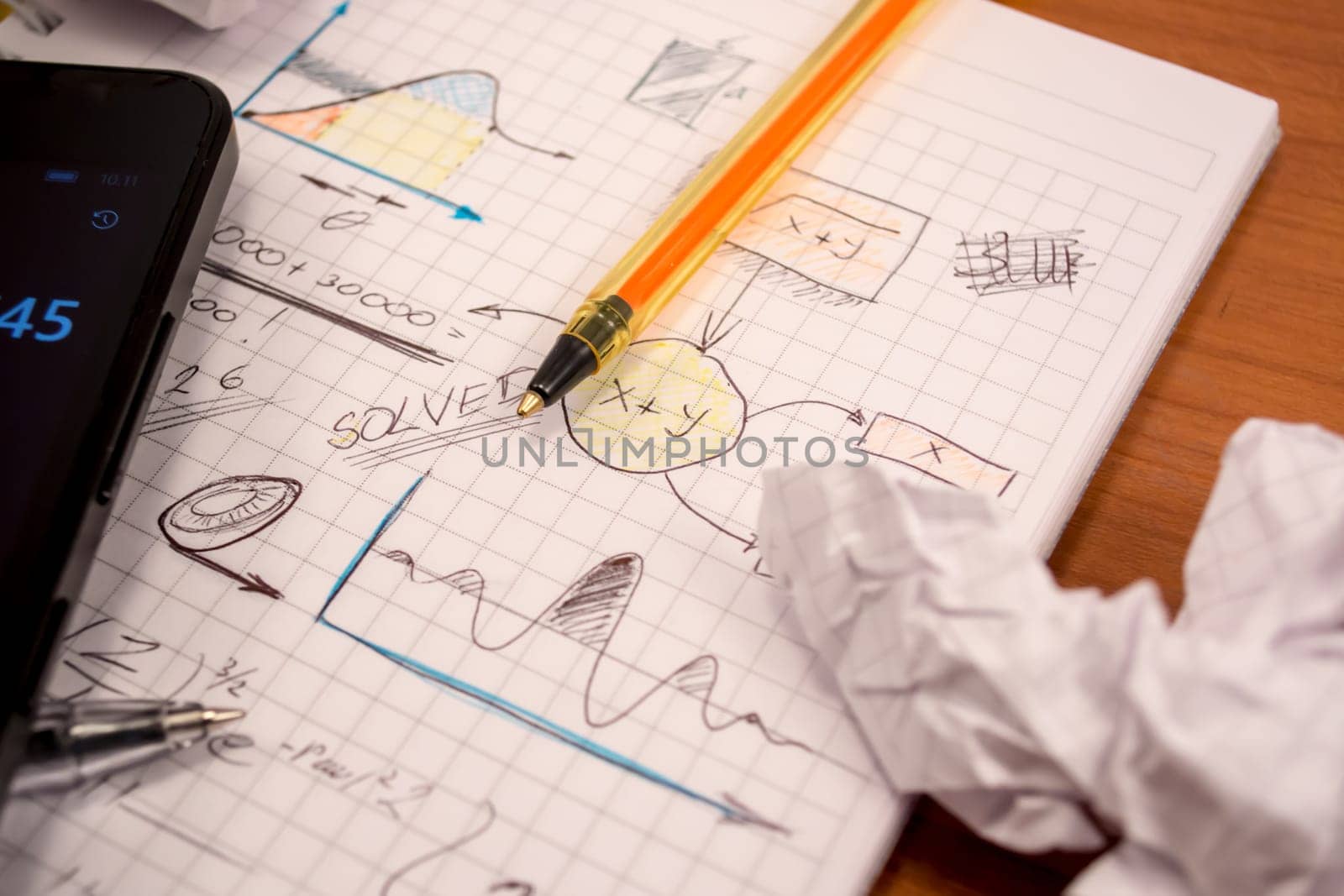 Notebook full of mathematics. Smart phone, pencils and crumpled paper are visible