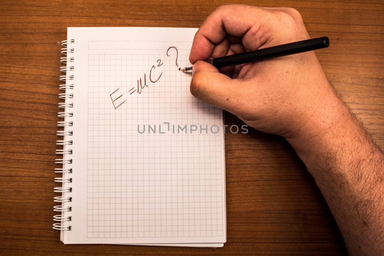 Hand with pencil and notebook. Hand written formula for transforming mass in to a energy