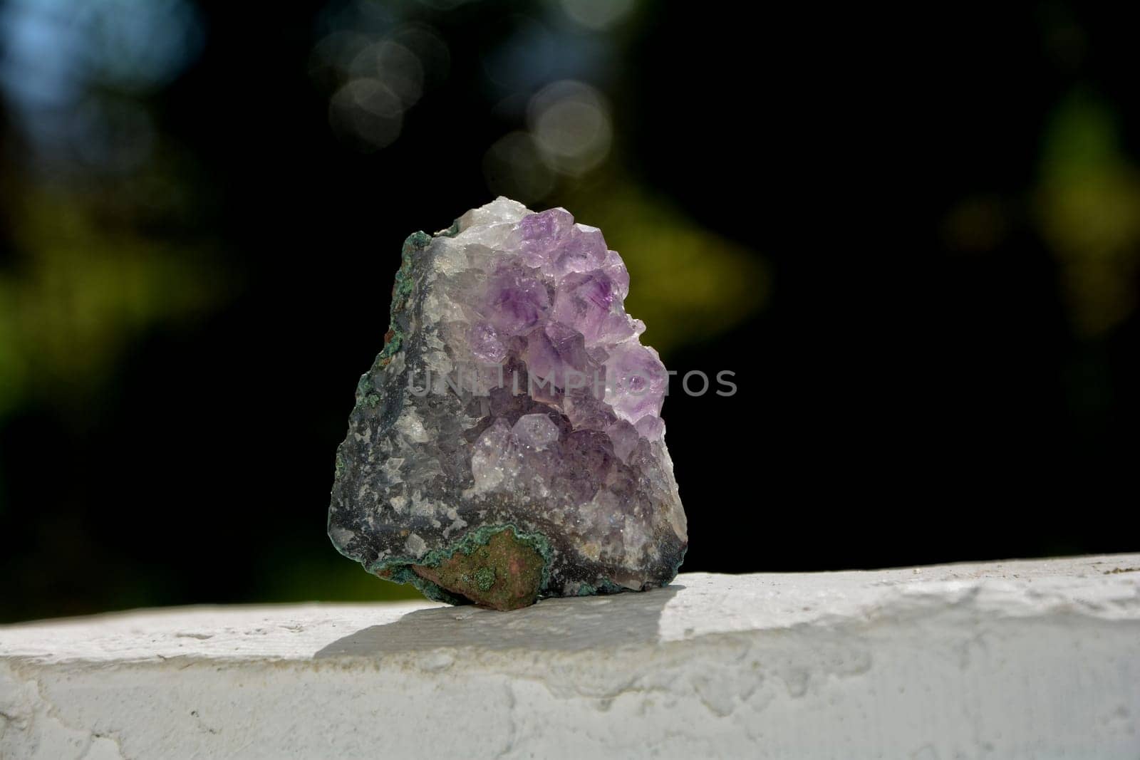 Purple amethyst on white wall against a green background