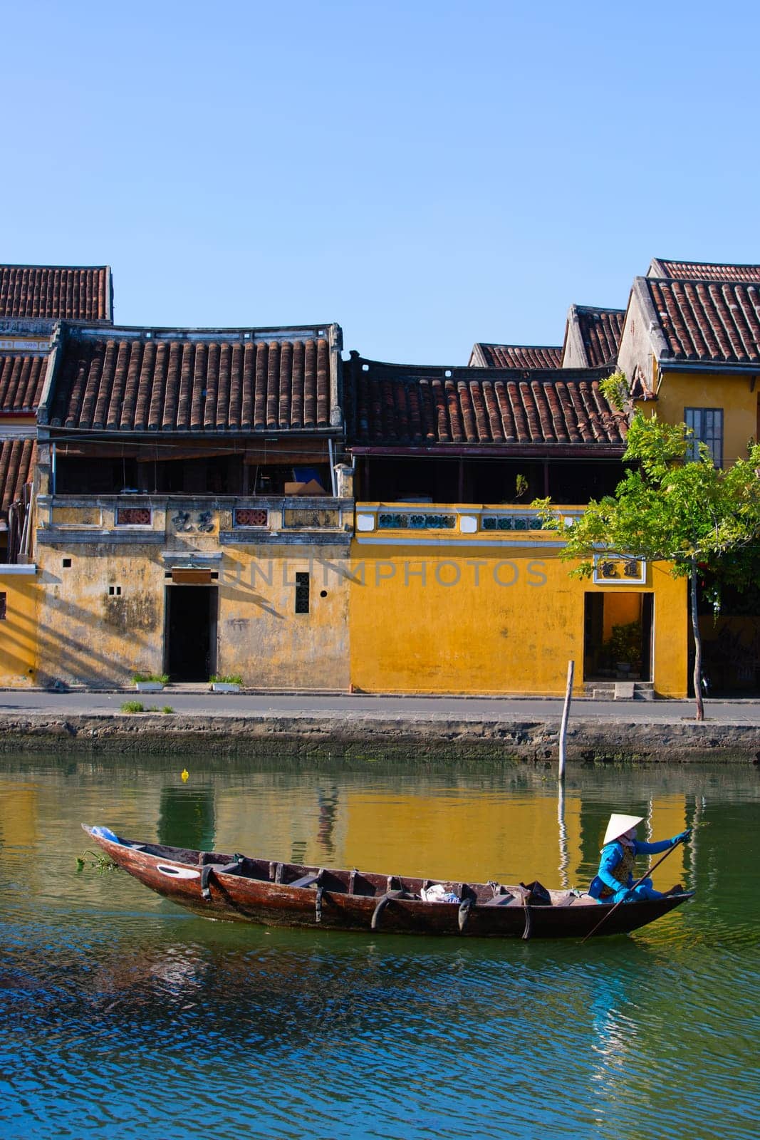 Local Vietnamese woman paddling her boat on the Thu Bon river in the old town of Hoi An .