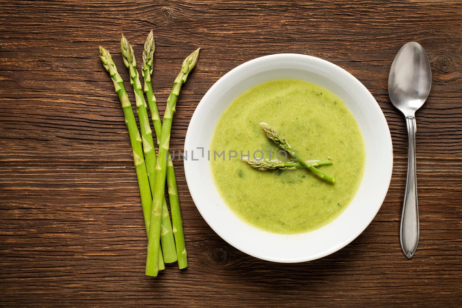 Fresh asparagus soup on wooden background overhead shoot