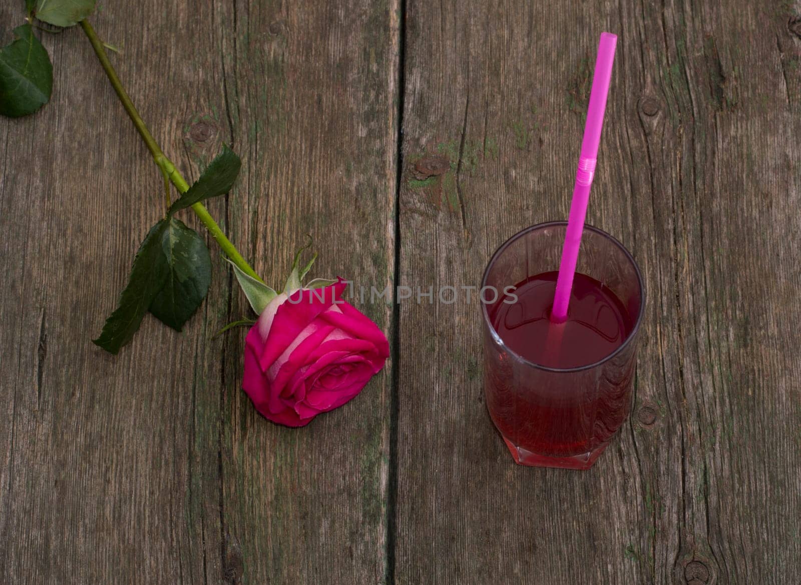 glass of juice and lonely red rose on a table