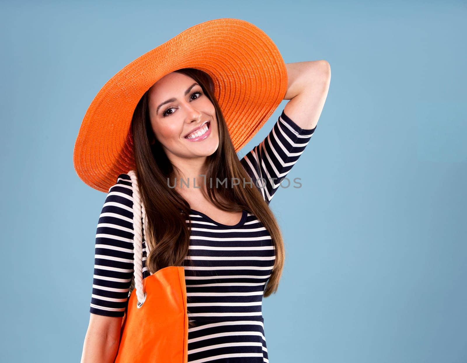 young woman wearing dress and orange hat on blue background
