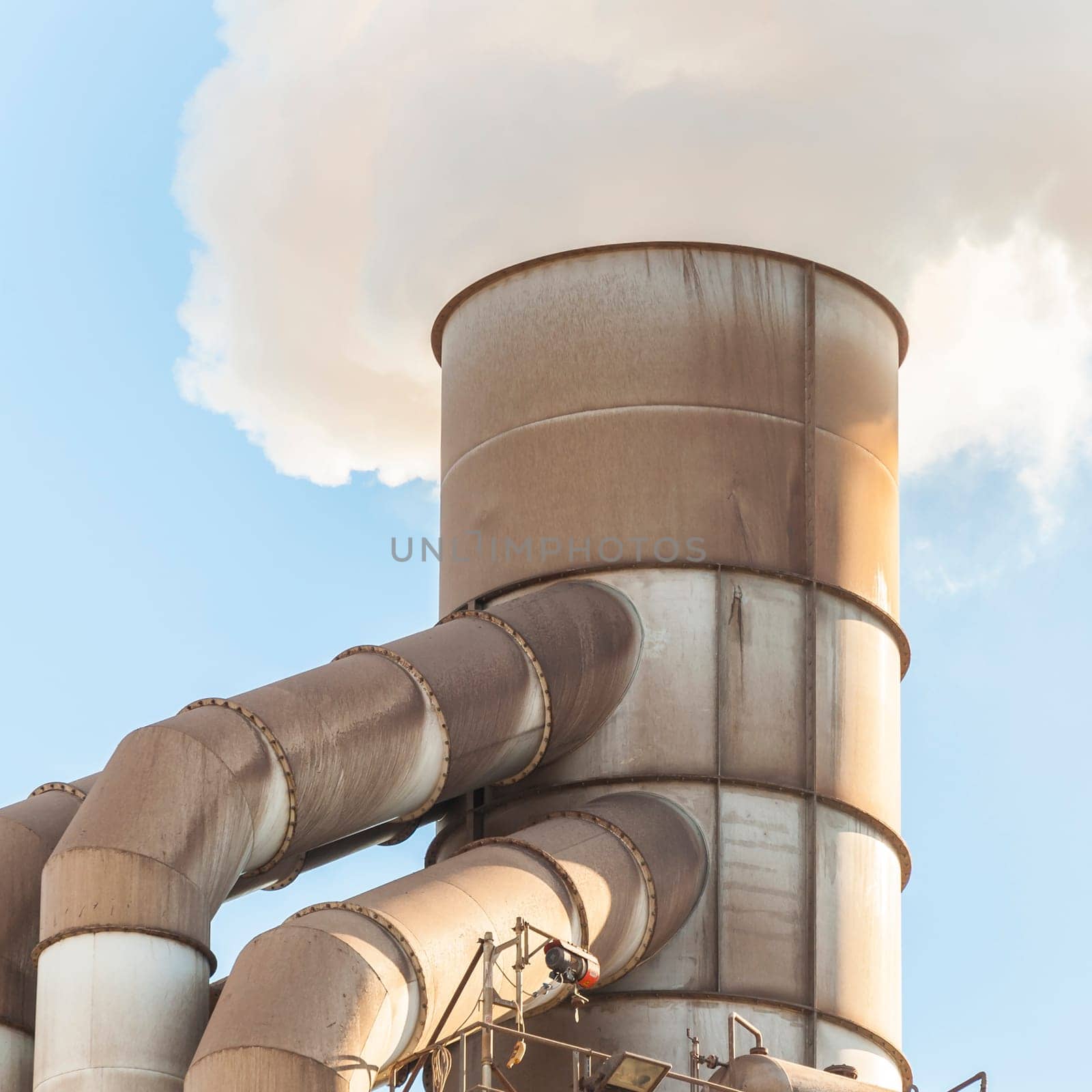Old smokestack that emits white smoke.