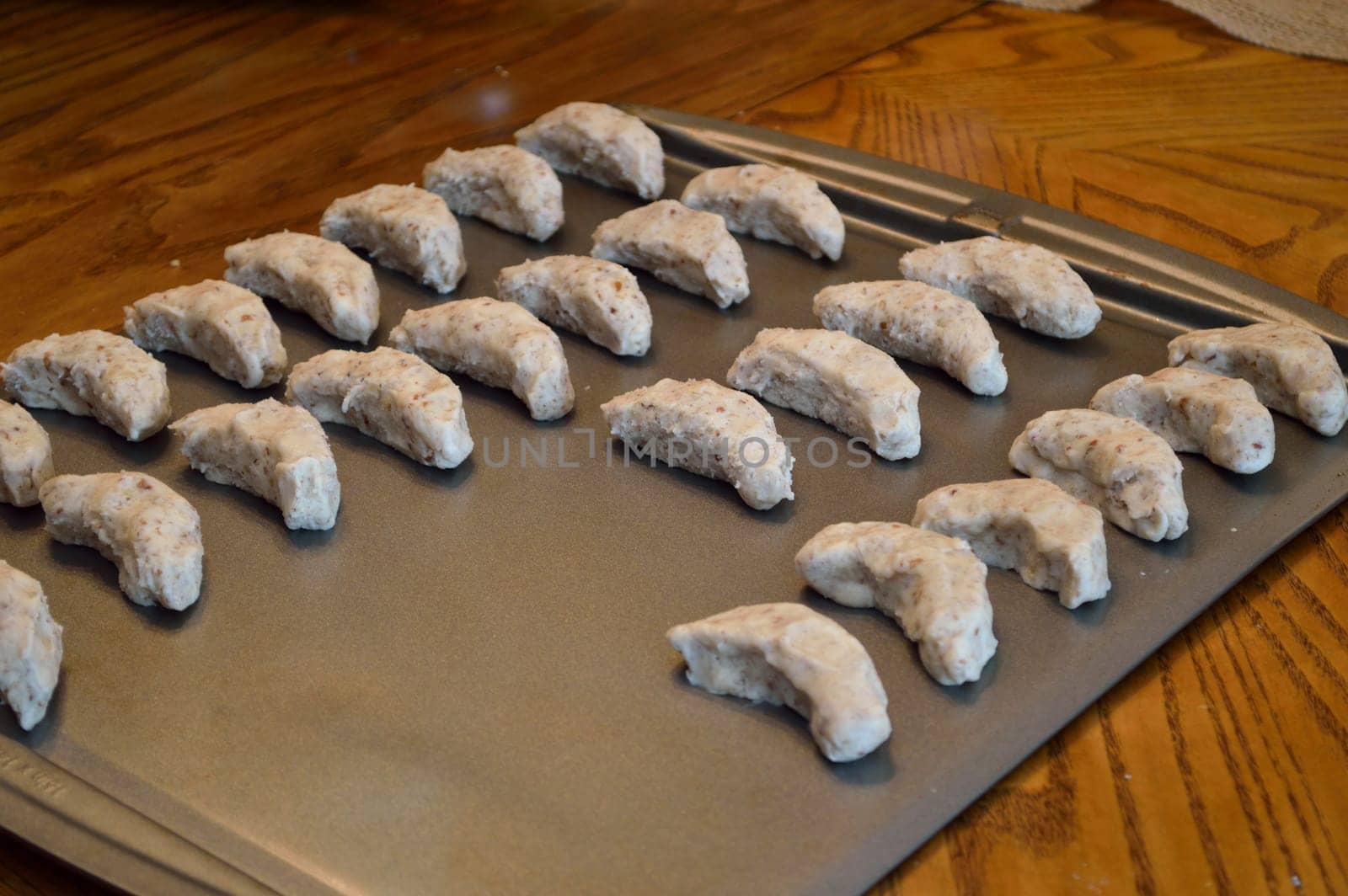 Raw cookie dough, on baking sheet ready to go in the oven. Crescent cookies in moon shapes.