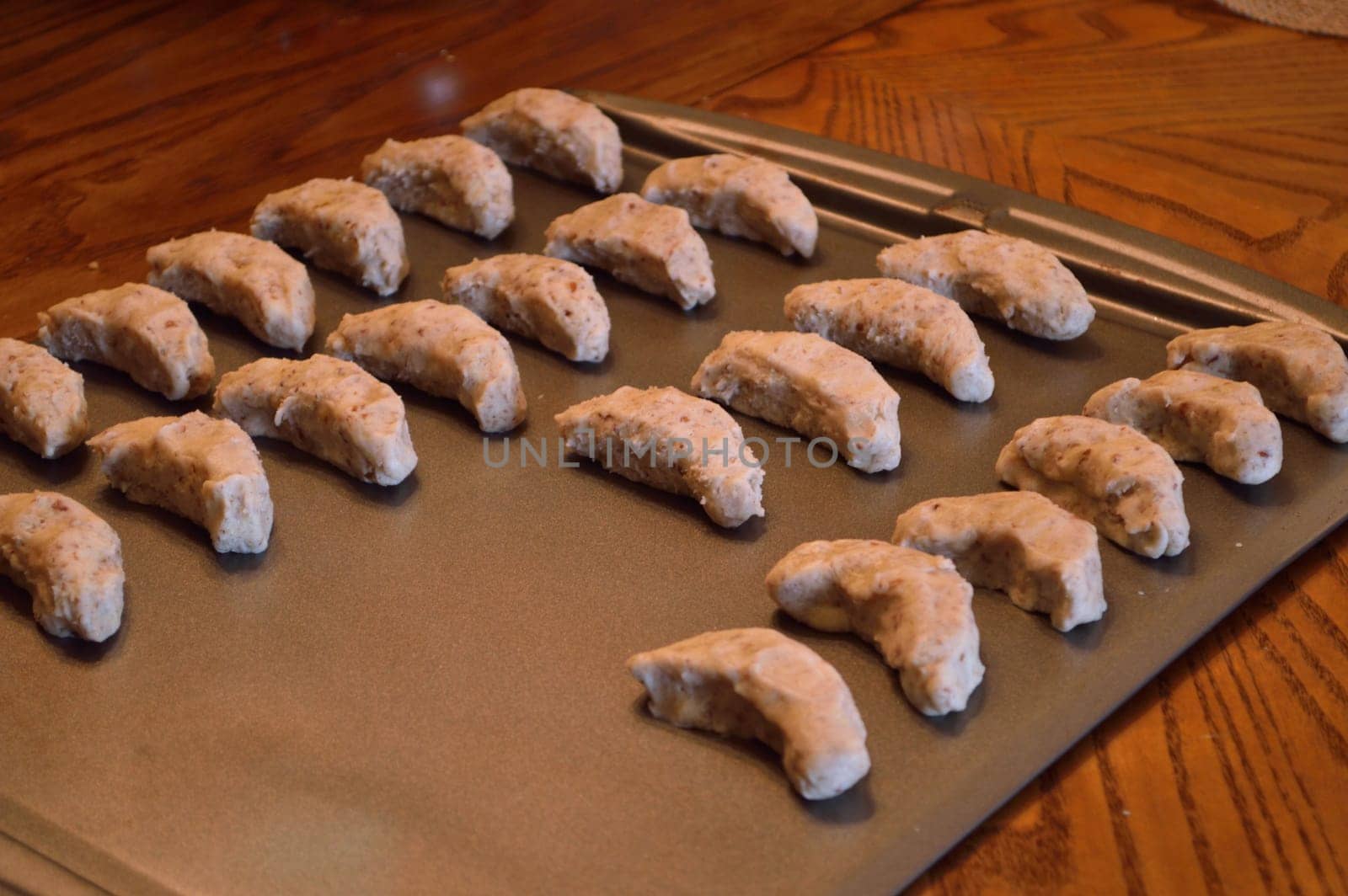 Raw cookie dough, on baking sheet ready to go in the oven. Crescent cookies in moon shapes.